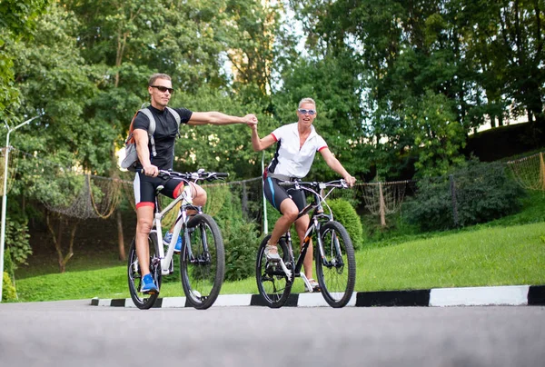 Erkek ve kadın el ele bisiklete biniyor.