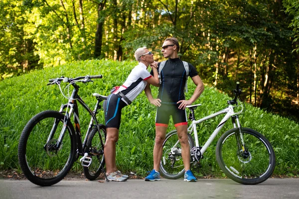 Bisikletli atletik bir adam ve kadın, bir kadın başını ve ellerini erkek omzuna koydu.