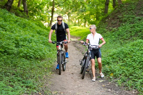 Bisikletli bir adam ve bir kadın tepeden aşağı iner..