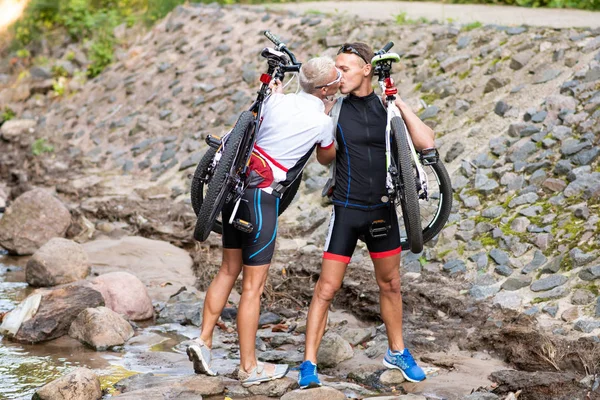 Omuzlarında bisiklet olan bir adam ve bir kadın öpüşüyor..