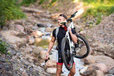 Omzunda bisiklet olan bir adam nehri geçer ve elini uzatır..