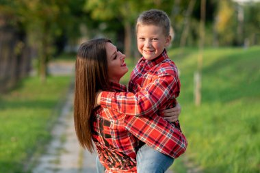 Annesi oğlunu kollarında tutuyor, gülümsüyor..