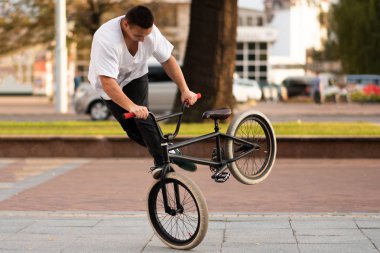 Dublör bisikletteki adam motoru ön tekerleğin etrafında döndürüyor..