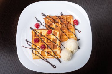 Dondurma, çikolata ve kirazlı Viyana waffleları. Yakın plan. Tabakta.