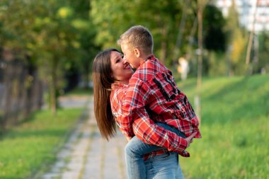 Anne gülümseyerek oğlunu kollarına aldı..