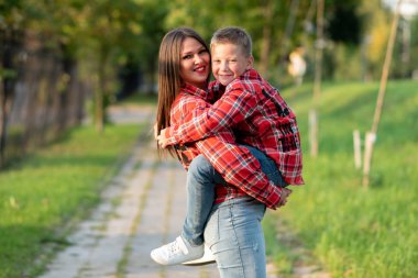 Anne gülümseyerek oğlunu kollarına aldı..