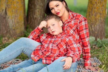 Anne ve oğul yatak örtüsünde oturuyorlar nazikçe sarılıyorlar.