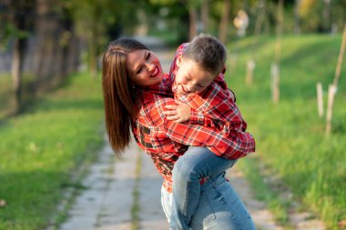 Anne, oyun oynarken, oğlunu kollarına aldı, her ikisi de güldü..