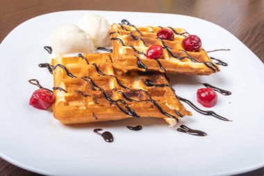 Dondurma, çikolata ve kirazlı Viyana waffleları. Yakın plan. Tabakta.