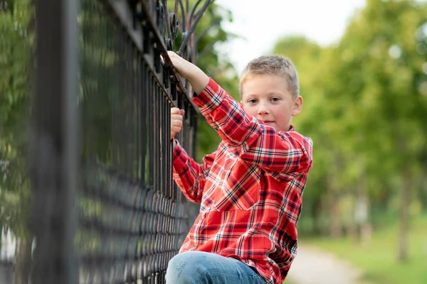 El chico subió la valla forjada . — Foto de Stock