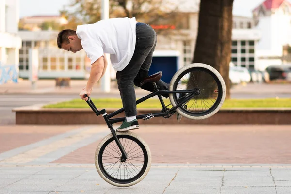 O cara na bicicleta BMX executa um truque na roda dianteira . — Fotografia de Stock