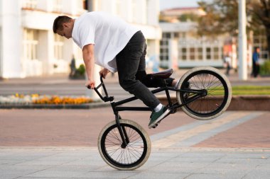 Bmx motorlu adam ön tekerlekte bir numara yapıyor..