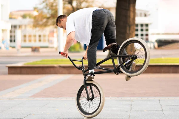 Der Typ auf dem BMX-Rad macht einen Trick am Vorderrad. — Stockfoto