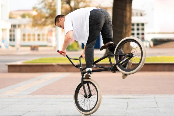 O cara na bicicleta BMX executa um truque na roda dianteira . — Fotografia de Stock