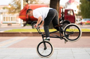 Bmx motorlu genç bir adam, ön tekere biniyor, ayağıyla fren yapıyor..