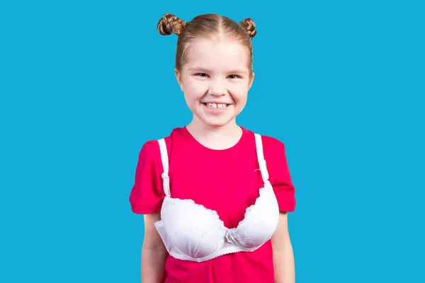 Kleines Mädchen im Mütter-BH, lächelnd. isoliert auf blauem Hintergrund. — Stockfoto