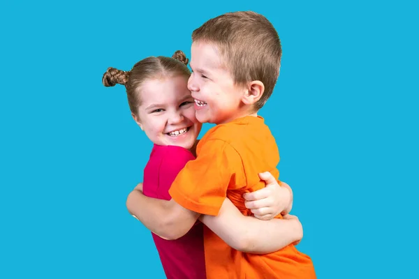 Bruder und Schwester umarmen sich isoliert auf blauem Grund. — Stockfoto