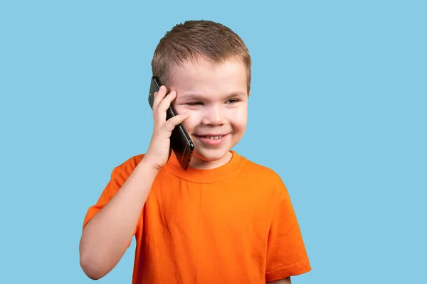 Kleine jongen is aan de telefoon. Geïsoleerd op een blauwe achtergrond. — Stockfoto