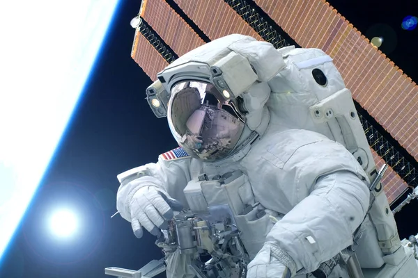 Astronaut i en rymddräkt, mot bakgrund av jorden, med solen bakom. Delar av denna bild tillhandahölls av Nasa. — Stockfoto