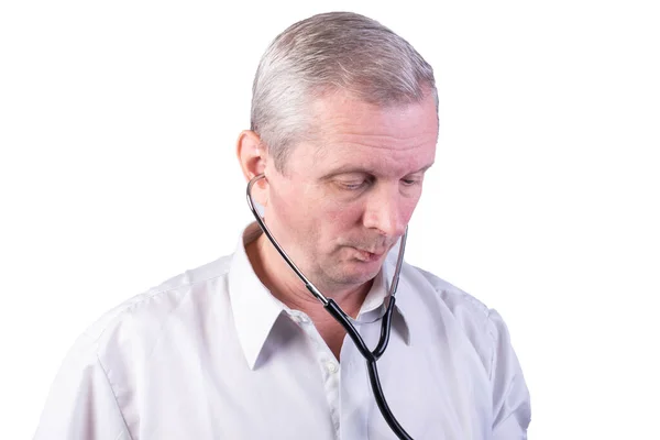 Elderly man with a stethoscope in his ears. Isolated on a white background. — Stock Photo, Image