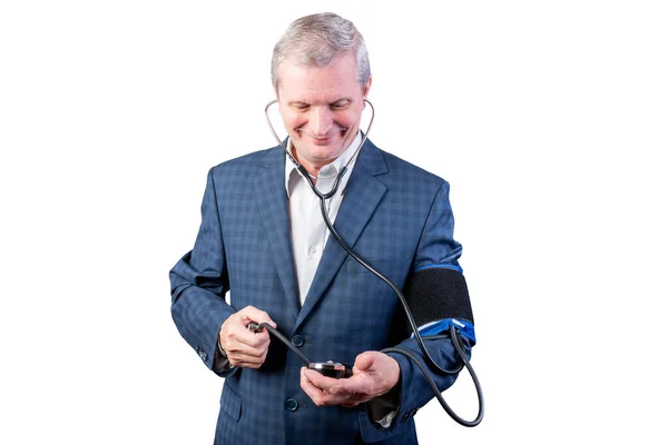 An elderly man in a suit measures pressure, by himself, with a hand tonometer. Isolated on a white background. — Stock Photo, Image