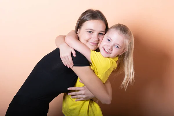 Duas meninas, irmãs, em um fundo laranja claro . — Fotografia de Stock