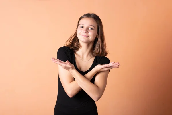 The girl points a finger to the right, on a light orange background. — Stock Photo, Image