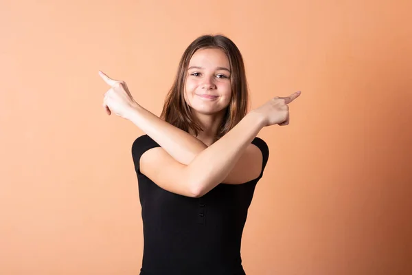 The girl points a finger to the right, on a light orange background.