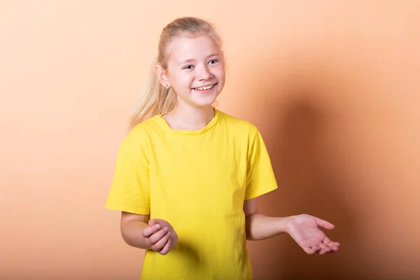 Beautiful girl at a loss on a light orange background.