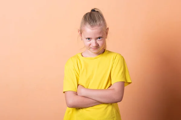 Flickan lade händerna på höfterna, på en ljusorange bakgrund. — Stockfoto