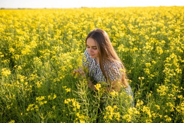 Saçı açık kanola tarlasında kanola koklayan bir kız. Yüksek kalite fotoğraf