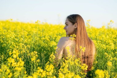 Kolza tohumu tarlasında omuzları açık güzel bir kız. Yüksek kalite fotoğraf