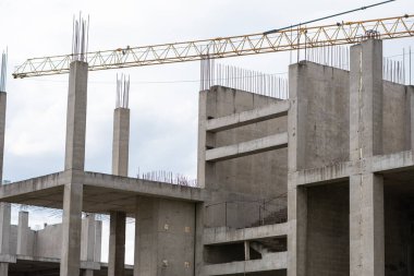Bulutlu havada güçlendirilmiş beton şantiye ve vinç.
