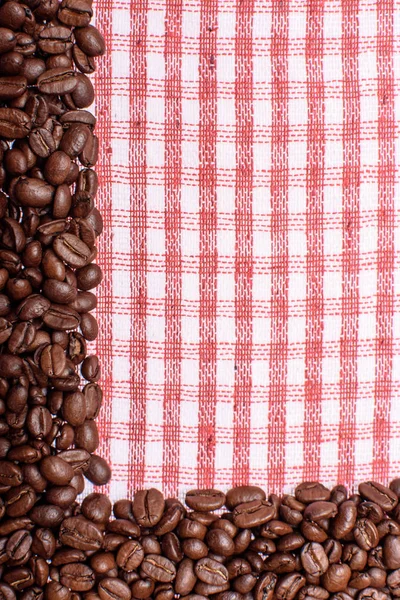 Textura de uma toalha colorida, uma toalha de um tipo celular, em que reside uma certa quantidade de grãos de café marrom. Vista superior com um monte de grãos de café com espaço para texto — Fotografia de Stock