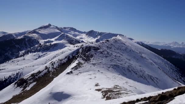 Panorama horizontal. Viele Menschen beginnen auf einer gut präparierten Skipiste in einem Skigebiet mit dem Skifahren. die Sonne scheint und der Himmel hell und klar ist — Stockvideo