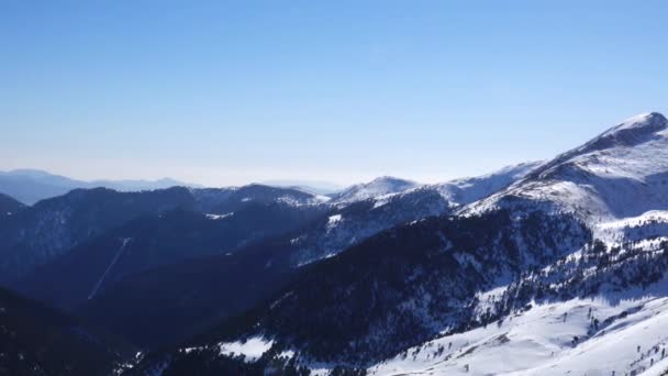 Panorama vodorovně. Mnoho lidí začíná lyžovat na dobře rozkveté lyžařské svahy v lyžařském letovisku. Slunce svítí a obloha je jasná a jasná — Stock video