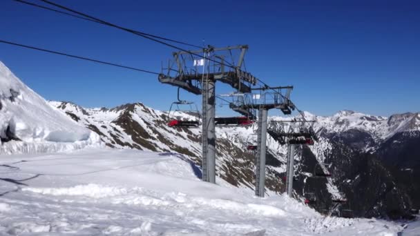 Panorama horisontell. Många människor börjar åka skidor på en välvårdad skidbacke på en skidort. Solen skiner och himlen är ljus och klar — Stockvideo