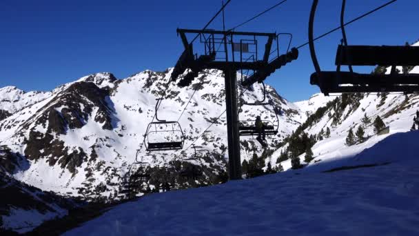 Панорама горизонтальная. Многие начинают кататься на лыжах на ухоженном горнолыжном курорте. Солнце светит, а небо ясное и ясное — стоковое видео