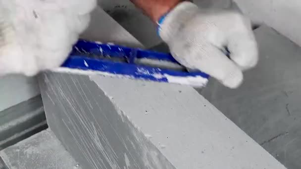 Работник делает ремонт квартиры, выравнивает край плитки с строгальщиком — стоковое видео