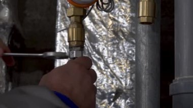 Tesisatçı bir anahtarı söker su borusundaki somunu sökür