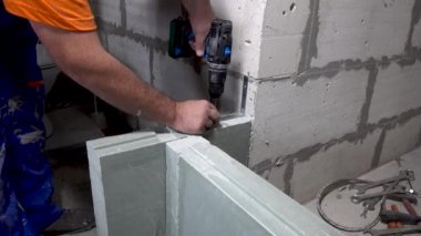 İşçi bir tornavida ile duvara bir köşe vidalar