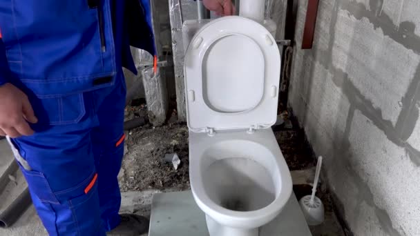 Rörmokare kontrollerar driften av toaletten, dränerar vattnet i toaletten — Stockvideo