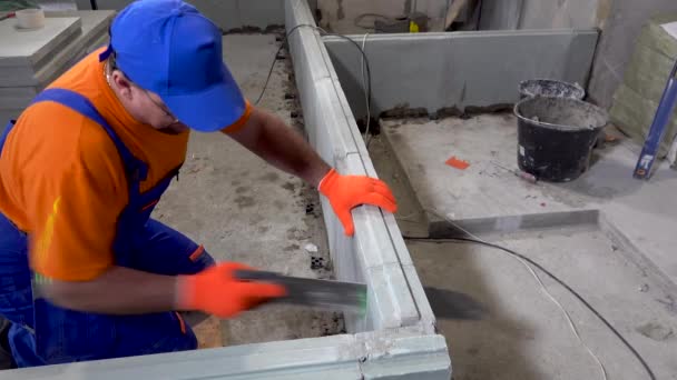 Repair in the apartment, a construction worker sawing plasterboard blocks — Stock Video