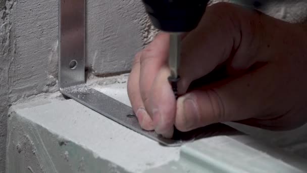 Worker screws a corner to the wall with a screwdriver — Stock Video