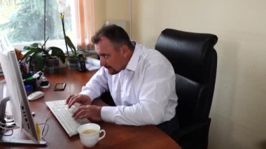 Genç adam şirketin müdürü ofiste oturur ve kahve içer