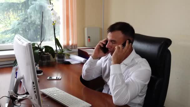 Young man the director of the company is sitting in the office emotionally talking on the phone — Stock Video