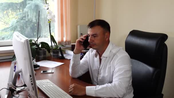 Jeune homme le directeur de la société est assis dans le bureau parlant émotionnellement au téléphone — Video