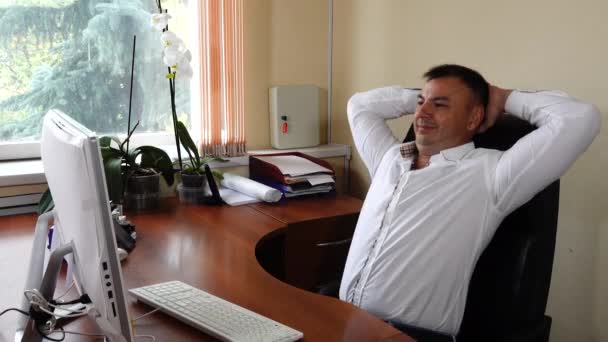 Il giovane il direttore dell'azienda siede in ufficio e lavora emotivamente, molto soddisfatto del suo lavoro. — Video Stock