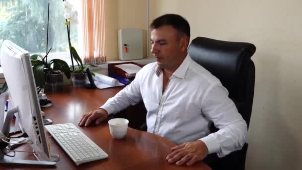 Young man the director of the company sits in the office and drinks coffee — Stock Video