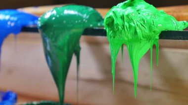 malalar yeşil ve mavi boya damlama. renkli boya damlama varil çim üzerinde trowers vardır. Mürekkep ya da parmak izi tee gömlek tee gömlek fabrikası için boya deposu